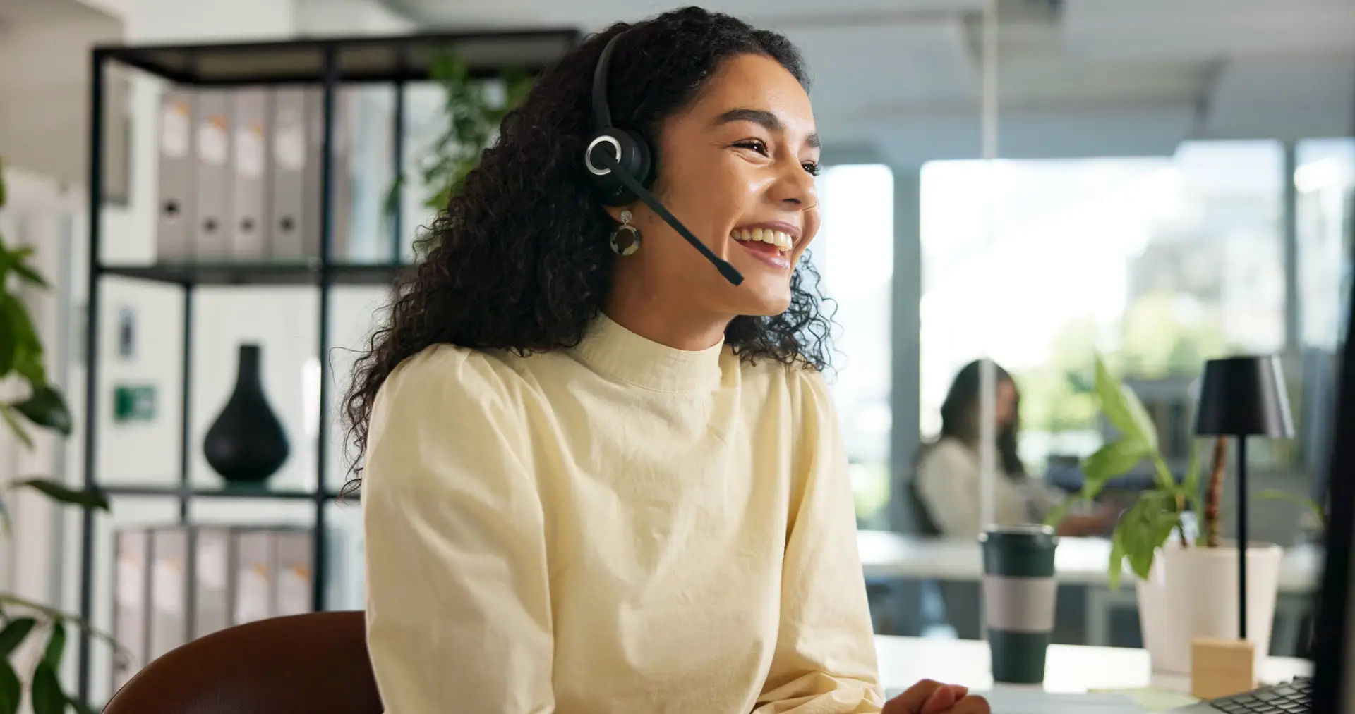 Customer service representative wearing a headset and smiling while assisting a customer in an office.
