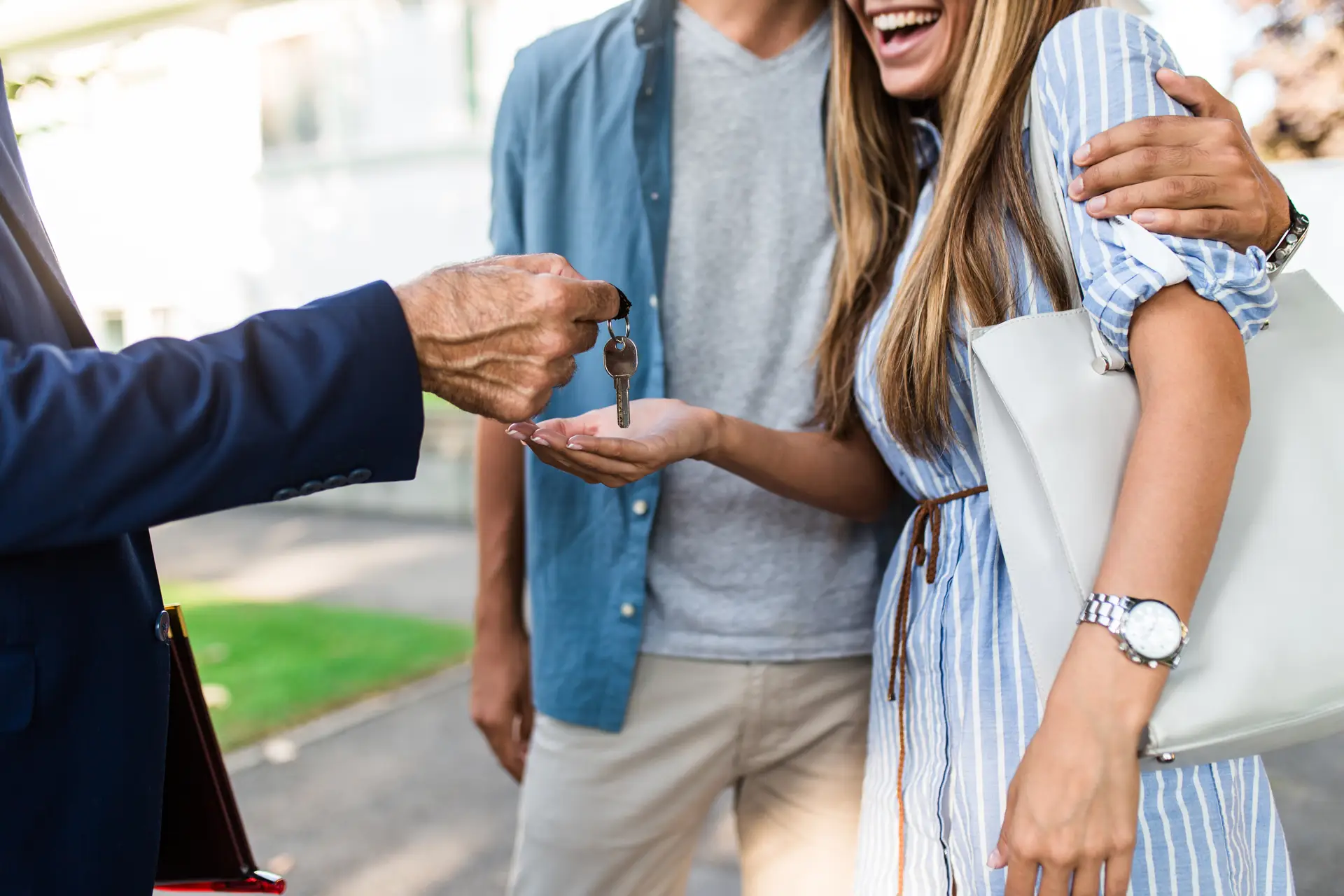 Real estate agent hands house keys to a smiling couple, celebrating the purchase of a new home.