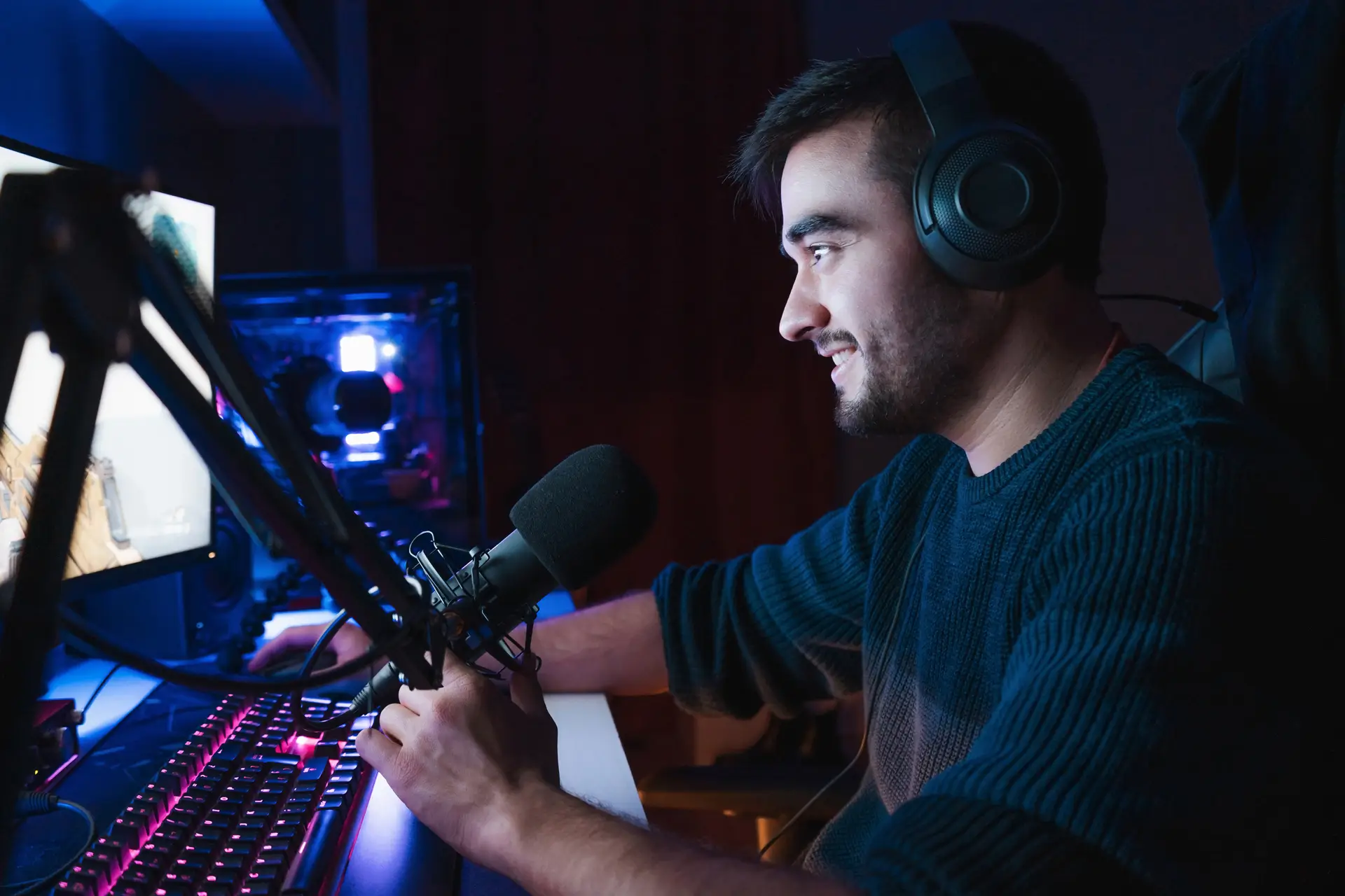 Person wearing headphones and speaking into a microphone while gaming or streaming at a computer.