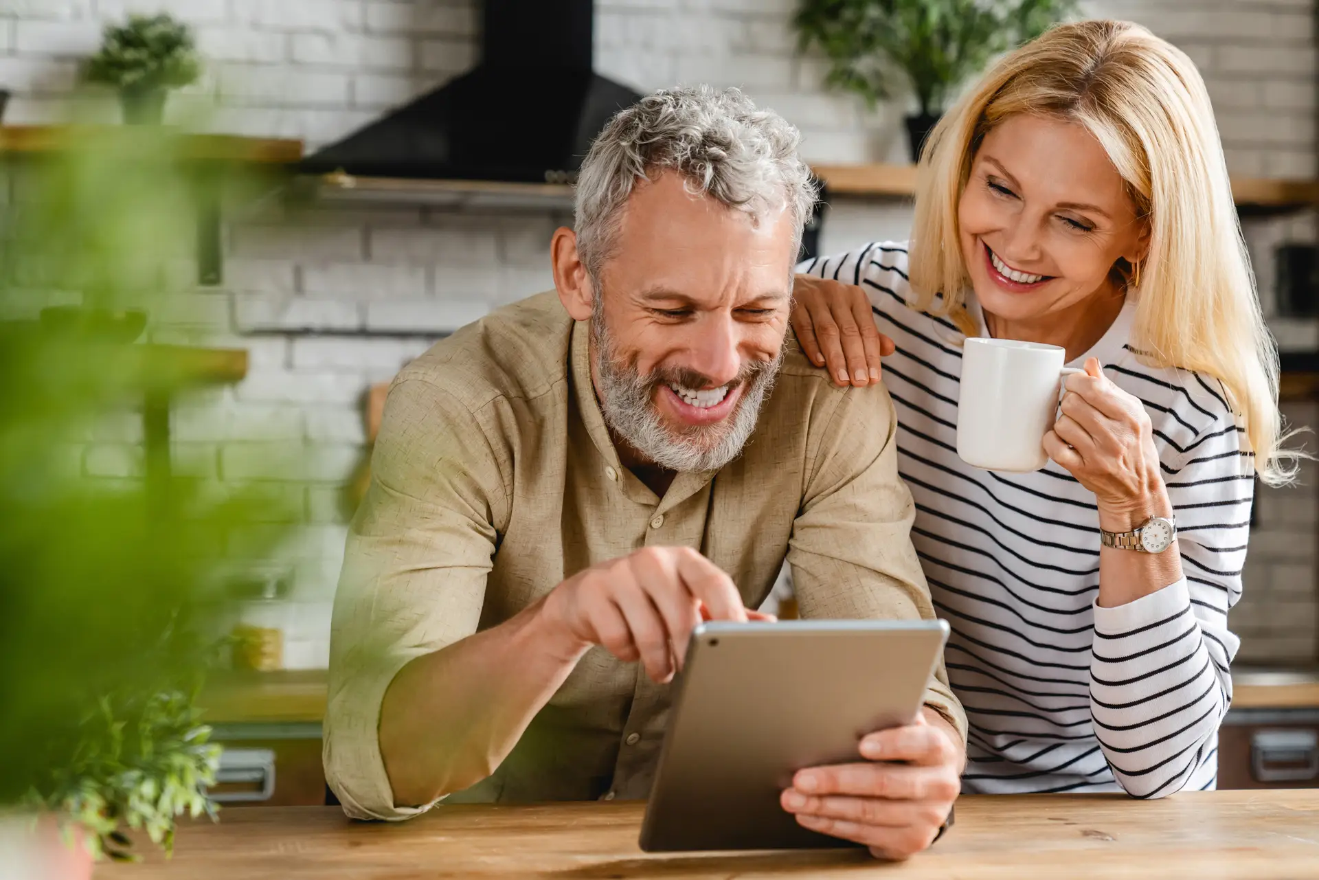 Two adults in a home kitchen setting looking at a tablet together.