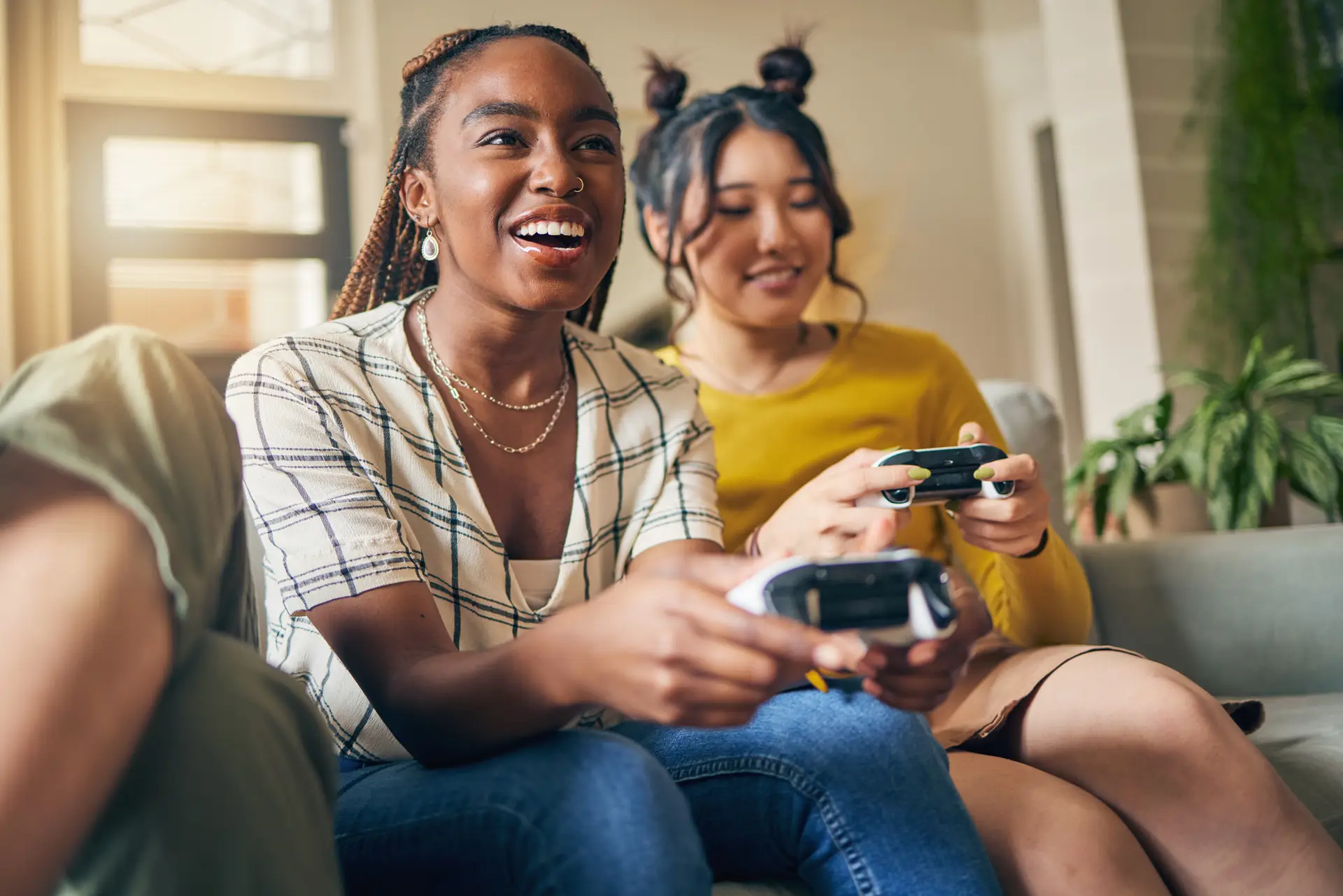 Two people sitting on a couch, smiling and playing a video game with handheld controllers.