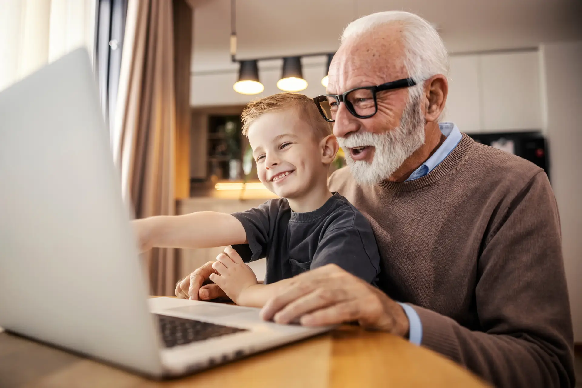 An older adult and child use a laptop together, demonstrating intergenerational learning and digital engagement at home.